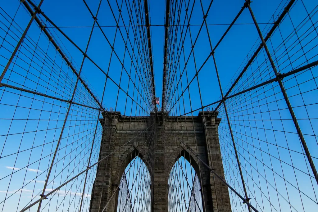 Walking the Brooklyn Bridge: Entrances, Timing, and What Changed in 2026 3 Looking up at a stone tower of the Brooklyn Bridge with the suspension cables radiating out