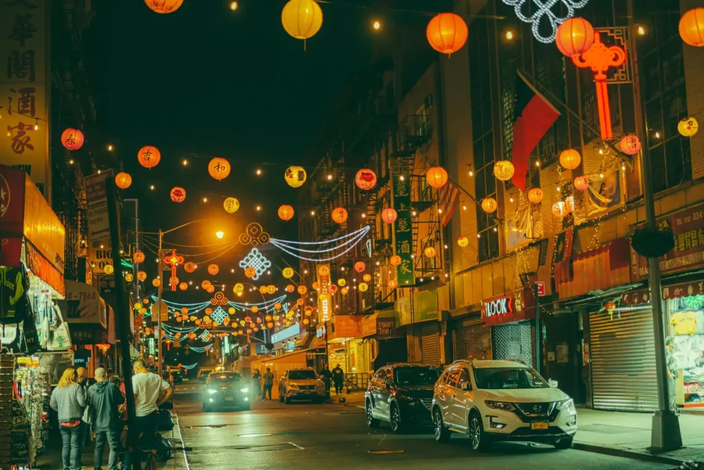 Cheap Eats in NYC: What Street Food Actually Costs 3 A street in Manhattan's Chinatown at night, lit with hanging paper lanterns above the shopfronts