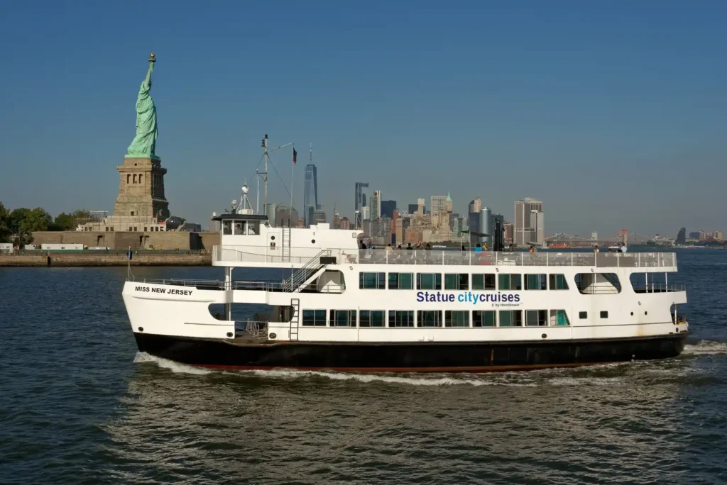Statue of Liberty and Ellis Island: Tickets, Ferries, and What the Guides Miss 1 A Statue City Cruises ferry passing Liberty Island, with the Statue of Liberty and the Lower Manhattan skyline behind