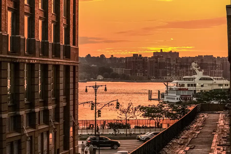 The High Line NYC: Complete Visitor Guide (Free, Hours & Tips) 3 Golden sunset over the Hudson River seen from the High Line in New York City with the New Jersey skyline and a yacht on the water